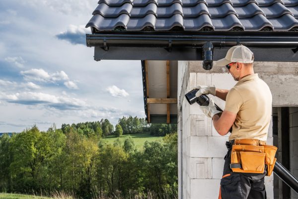 Construction Contractor Roof Worker Installing House Gutters. Construction Site Theme.
